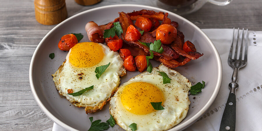 Fried eggs with bacon and cherry tomatoes.