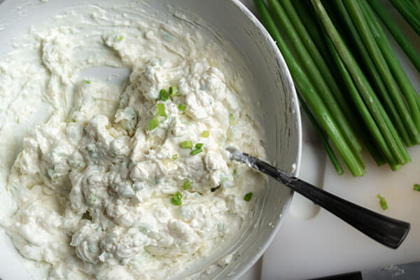 Adding green onions to dip.