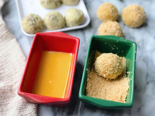 Coating the rice balls with pork rinds.