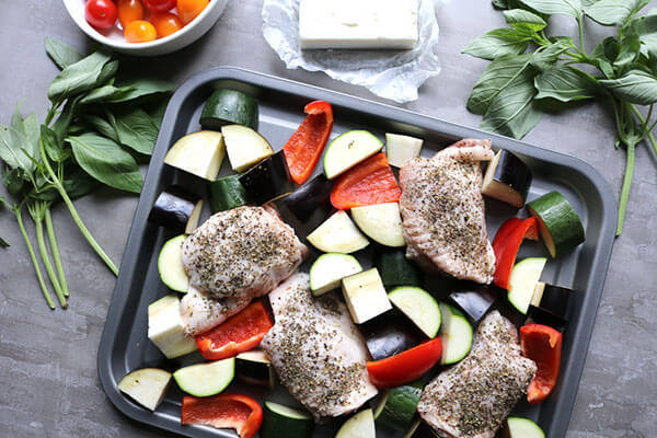 Chicken and chopped vegetables on a baking sheet.