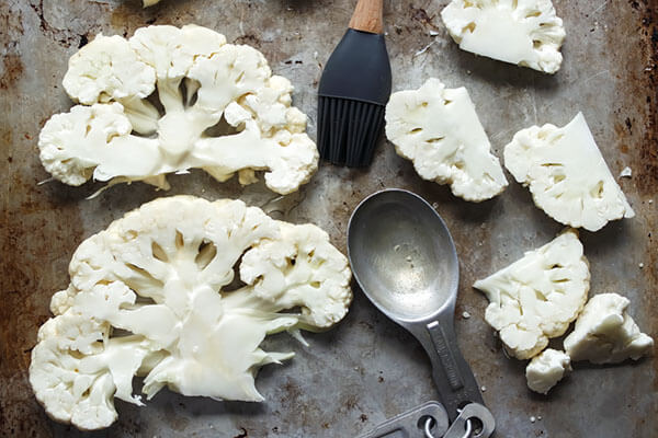 Cauliflower steaks on a baking sheet.